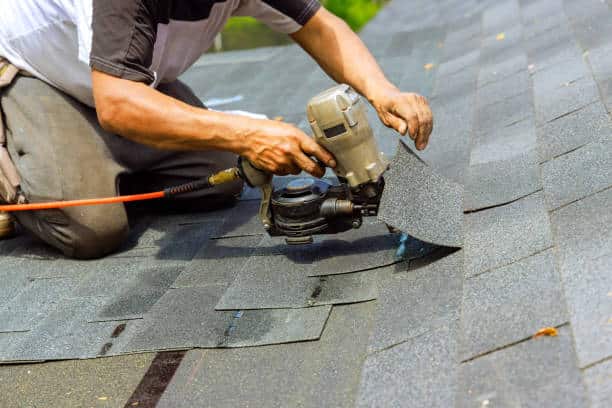 Roofer repairing roof by replacing shingles
